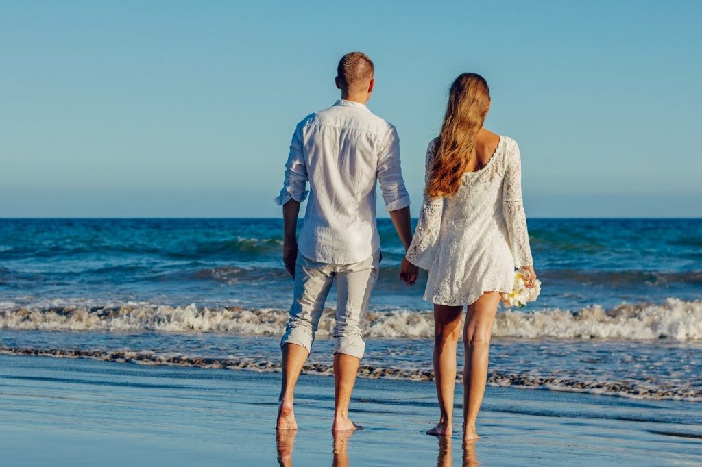 Man and woman holding hands by the beach