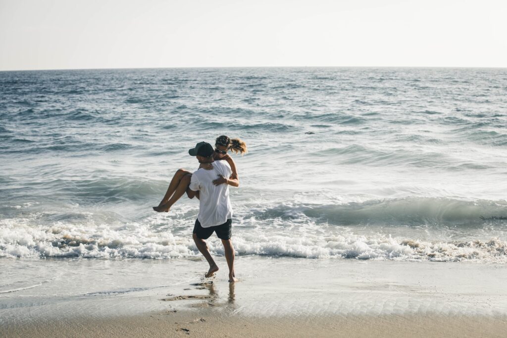 Man carrying woman on the beach at Honeymoon Hotel Labuan Bajo